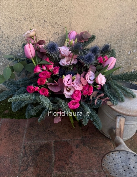 Mazzo di fiori sui toni rosa e fucsia con un tocco di verde natalizio 